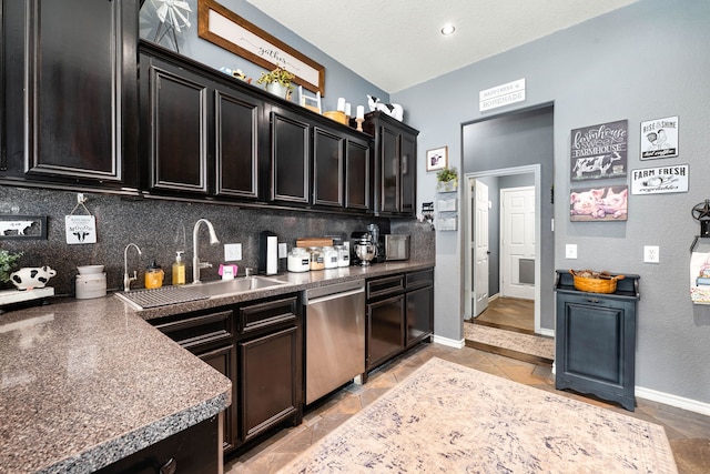 kitchen with tasteful backsplash, baseboards, dark countertops, stainless steel dishwasher, and a sink