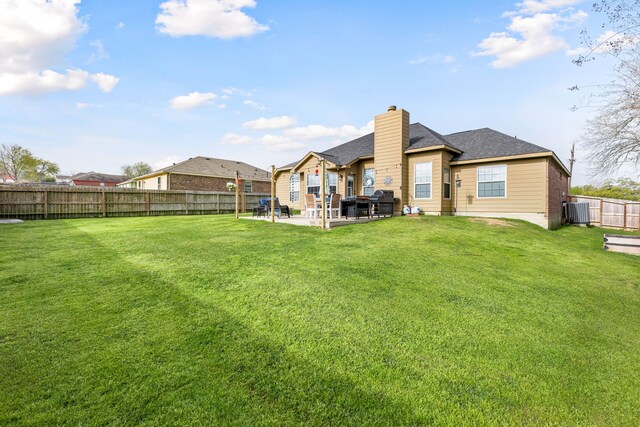 rear view of property featuring a chimney, a patio area, central AC, a fenced backyard, and a yard