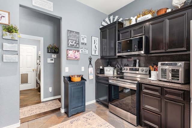 kitchen featuring dark countertops, washer / dryer, stainless steel appliances, baseboards, and a toaster
