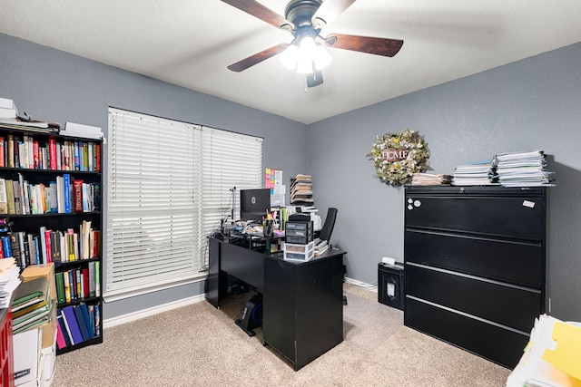 carpeted office featuring baseboards and a ceiling fan