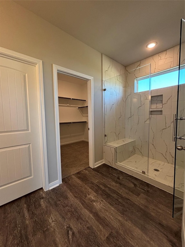 full bath featuring wood finished floors, recessed lighting, a marble finish shower, baseboards, and a spacious closet