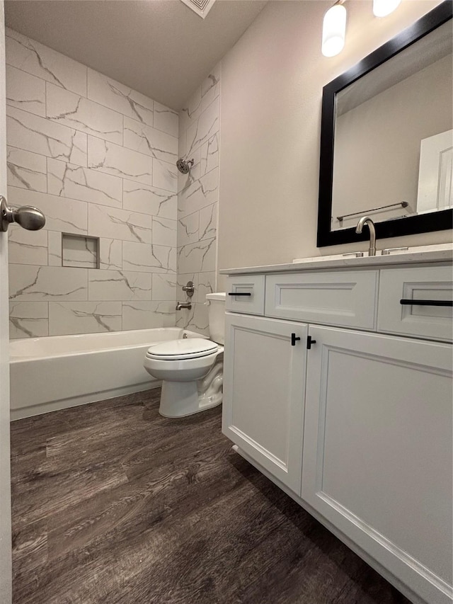 bathroom featuring vanity, washtub / shower combination, toilet, and wood finished floors