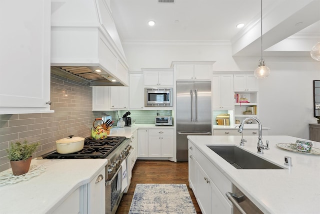 kitchen with white cabinets, built in appliances, light countertops, and a sink