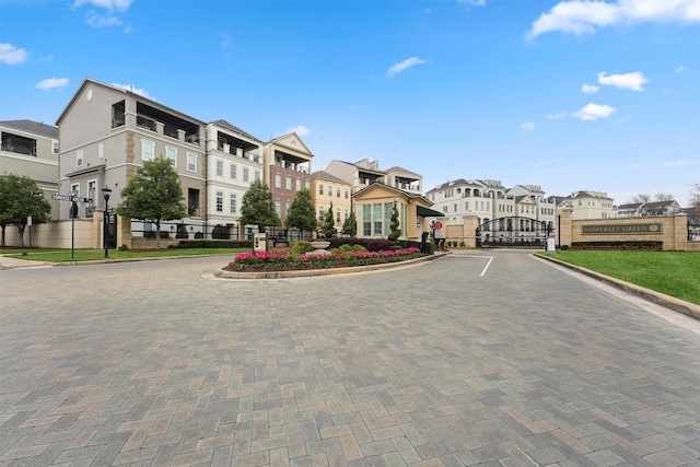 view of street featuring a residential view, a gate, a gated entry, traffic signs, and curbs