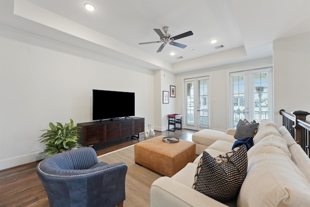 living room with a ceiling fan, wood finished floors, a raised ceiling, baseboards, and visible vents
