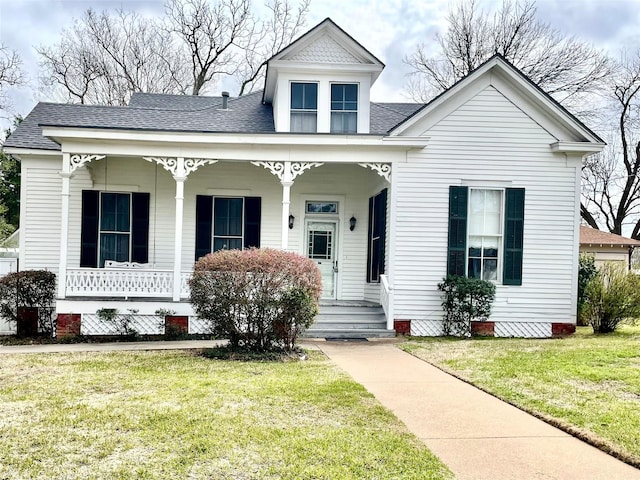 view of front facade featuring covered porch, roof with shingles, and a front lawn
