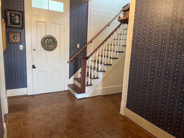 entrance foyer featuring wallpapered walls, stairs, and baseboards