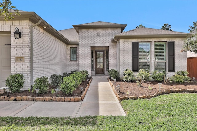 122 S Wild Petunia Trl, Montgomery, TX 77316 - property entrance featuring brick siding, a garage, and a shingled roof