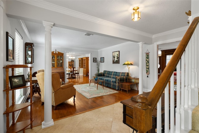 living room with ornate columns, light tile patterned flooring, ornamental molding, and a healthy amount of sunlight