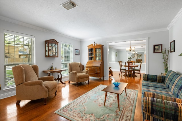 living room featuring crown molding, a healthy amount of sunlight, wood finished floors, and visible vents