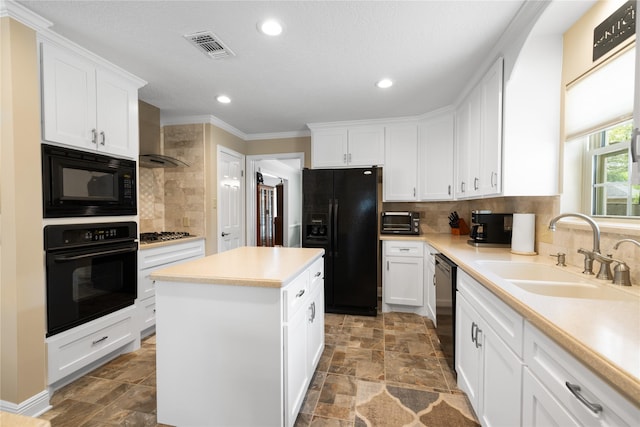 kitchen featuring a sink, stone finish floor, black appliances, and white cabinetry