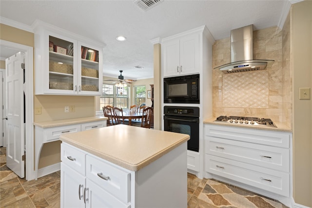 kitchen featuring decorative backsplash, glass insert cabinets, ceiling fan, wall chimney exhaust hood, and black appliances