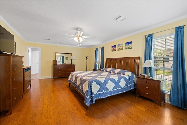 bedroom featuring ornamental molding, wood finished floors, and visible vents