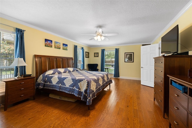 bedroom featuring crown molding, a textured ceiling, baseboards, and wood finished floors
