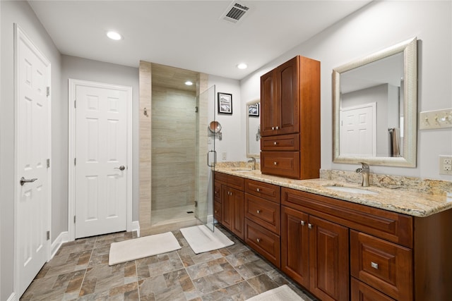 full bathroom featuring a sink, a shower stall, double vanity, and visible vents