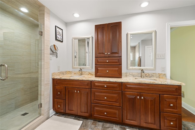 bathroom with double vanity, a shower stall, and a sink