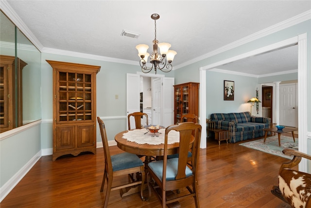 dining area with visible vents, wood finished floors, baseboards, a notable chandelier, and ornamental molding
