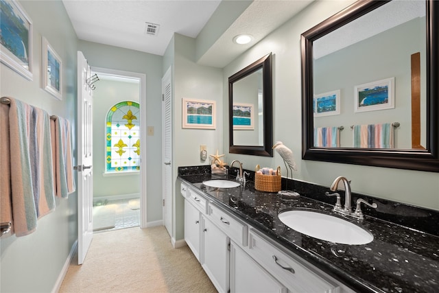bathroom featuring a sink, baseboards, double vanity, and visible vents