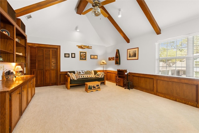 living area with wainscoting, light carpet, and beamed ceiling