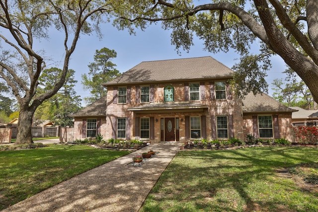 view of front of home with brick siding, roof with shingles, and a front yard