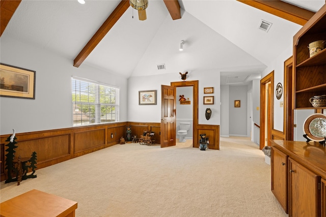 interior space featuring visible vents, lofted ceiling with beams, a wainscoted wall, and light carpet