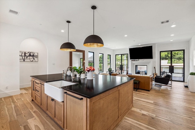 kitchen with light wood-type flooring, visible vents, and dark countertops