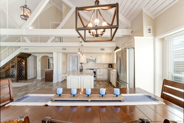 kitchen with tasteful backsplash, appliances with stainless steel finishes, a kitchen island, and an inviting chandelier