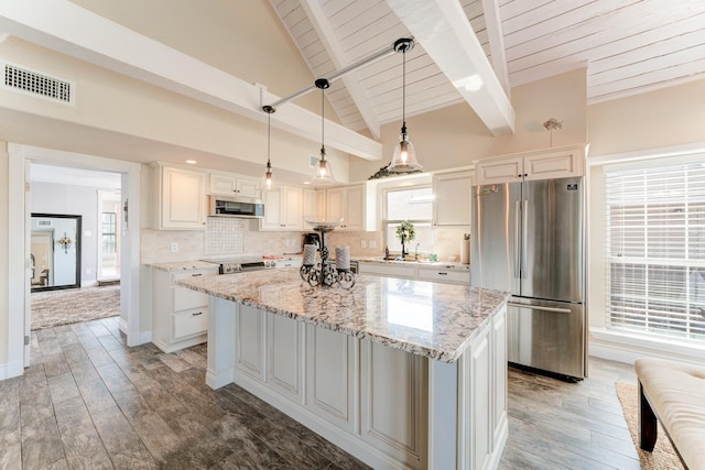 kitchen with visible vents, backsplash, a kitchen island, lofted ceiling with beams, and appliances with stainless steel finishes