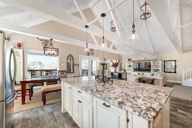 kitchen featuring light stone countertops, beamed ceiling, freestanding refrigerator, hanging light fixtures, and dark wood-style flooring
