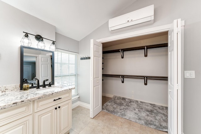 bathroom featuring baseboards, an AC wall unit, vaulted ceiling, tile patterned floors, and vanity