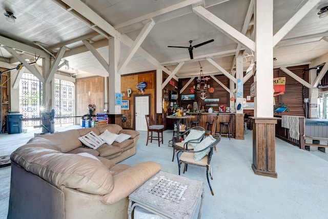 living room with a ceiling fan and wood walls