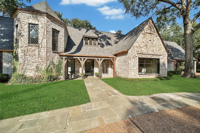 view of front of property with a front yard, brick siding, and a shingled roof