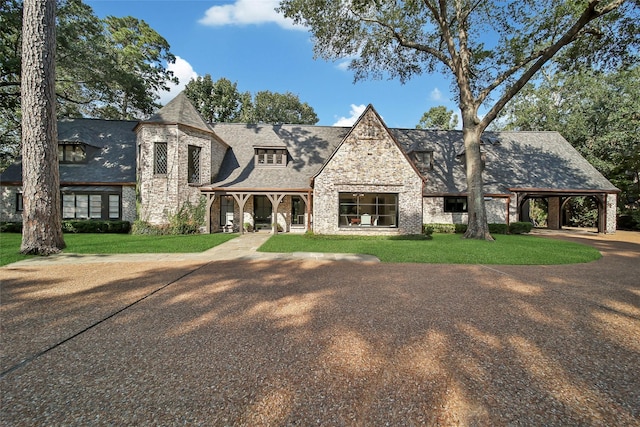 view of front facade with a front lawn, stone siding, and a shingled roof