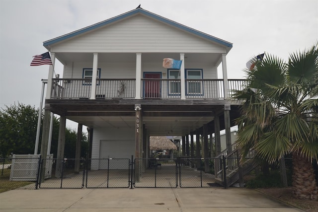 4031 Hardin Dr, Galveston, TX 77554 - view of front of home with concrete driveway, a carport, a balcony, a garage, and a gate