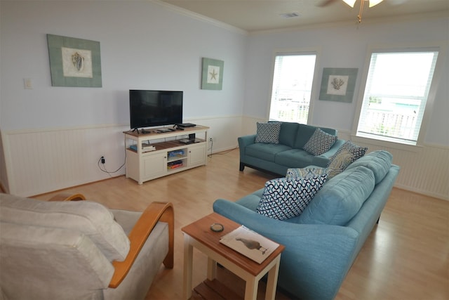 4031 Hardin Dr, Galveston, TX 77554 - living room featuring light wood-type flooring, a healthy amount of sunlight, crown molding, and a wainscoted wall