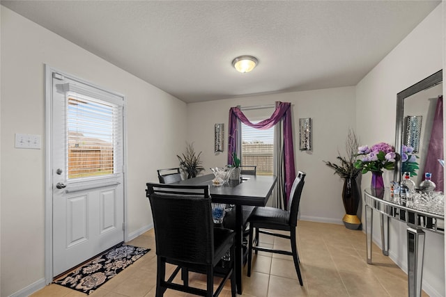 dining space featuring light tile patterned floors, baseboards, and a textured ceiling