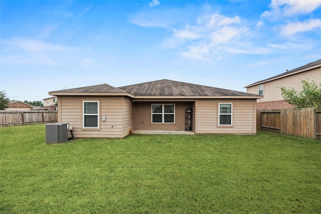 rear view of property featuring central air condition unit, a yard, and a fenced backyard