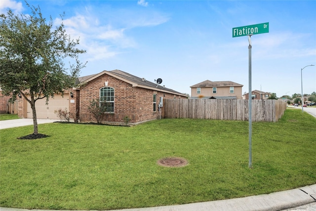view of yard with an attached garage, driveway, and fence