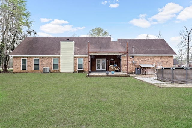 446 Piney Point Dr, Sour Lake, TX 77659 - back of property featuring french doors, a yard, an outdoor pool, brick siding, and central AC unit