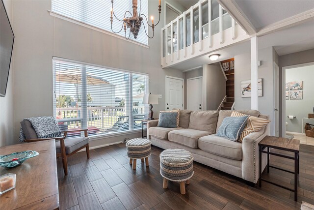 908 Calico Jack Cv, Galveston, TX 77554 - living room featuring a towering ceiling, dark wood-style flooring, stairs, a chandelier, and baseboards
