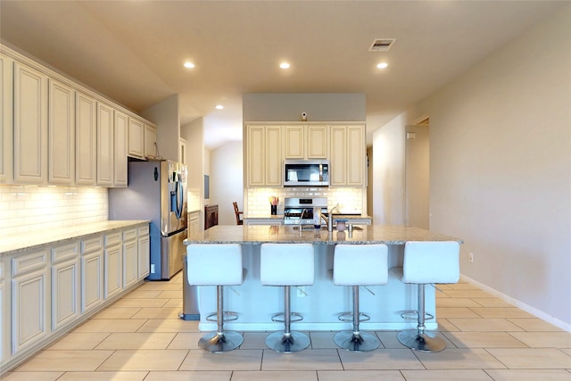 kitchen featuring visible vents, decorative backsplash, appliances with stainless steel finishes, and light stone counters