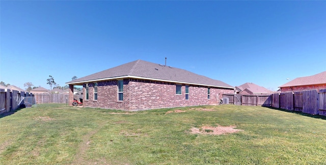 rear view of property featuring a lawn, a fenced backyard, and brick siding