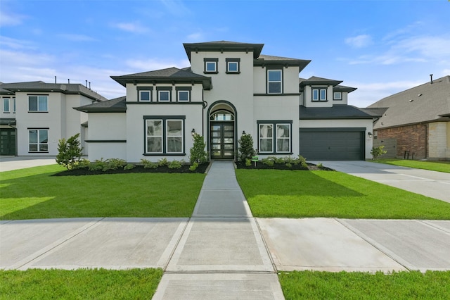 prairie-style house featuring stucco siding, concrete driveway, and a front lawn