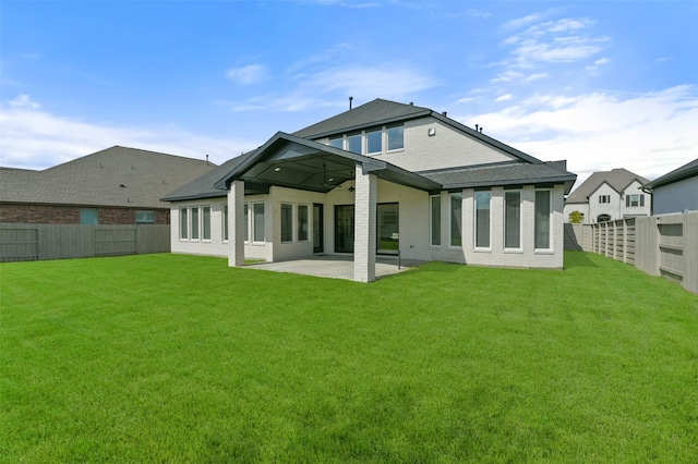 back of property with brick siding, a patio, a fenced backyard, and a lawn