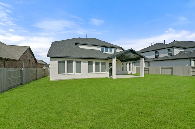 rear view of property with a yard, brick siding, and a fenced backyard