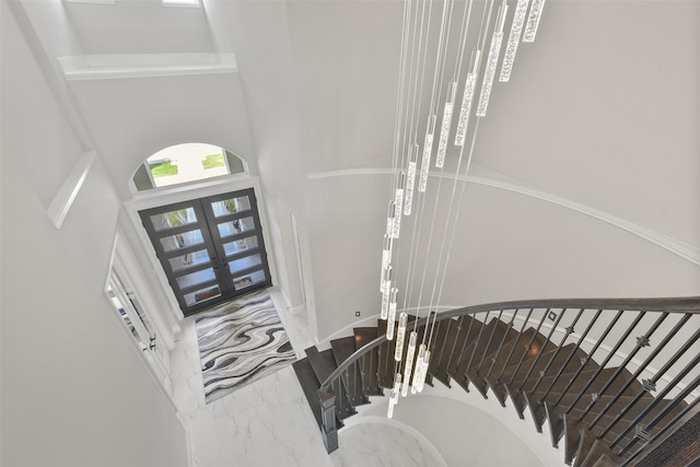 entryway with french doors, a high ceiling, marble finish floor, and stairs