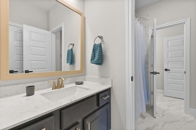 bathroom with marble finish floor, vanity, and baseboards