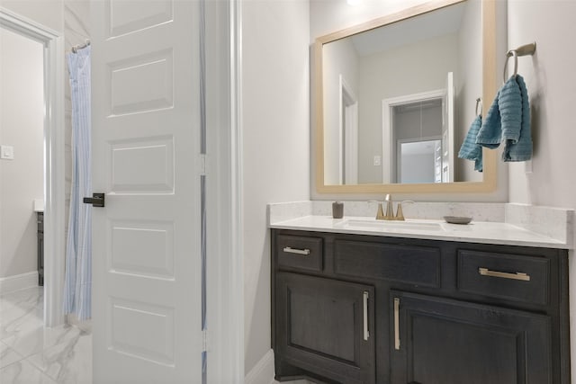 bathroom featuring baseboards, marble finish floor, and vanity