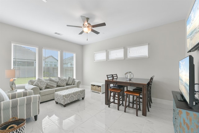 living area featuring visible vents, baseboards, marble finish floor, and a ceiling fan
