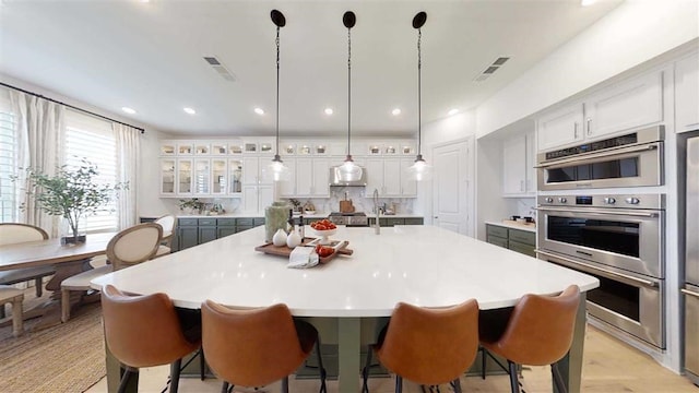 12043 Lake View Blvd, Mont Belvieu, TX 77523 - kitchen with light countertops, double oven, white cabinets, a large island, and glass insert cabinets